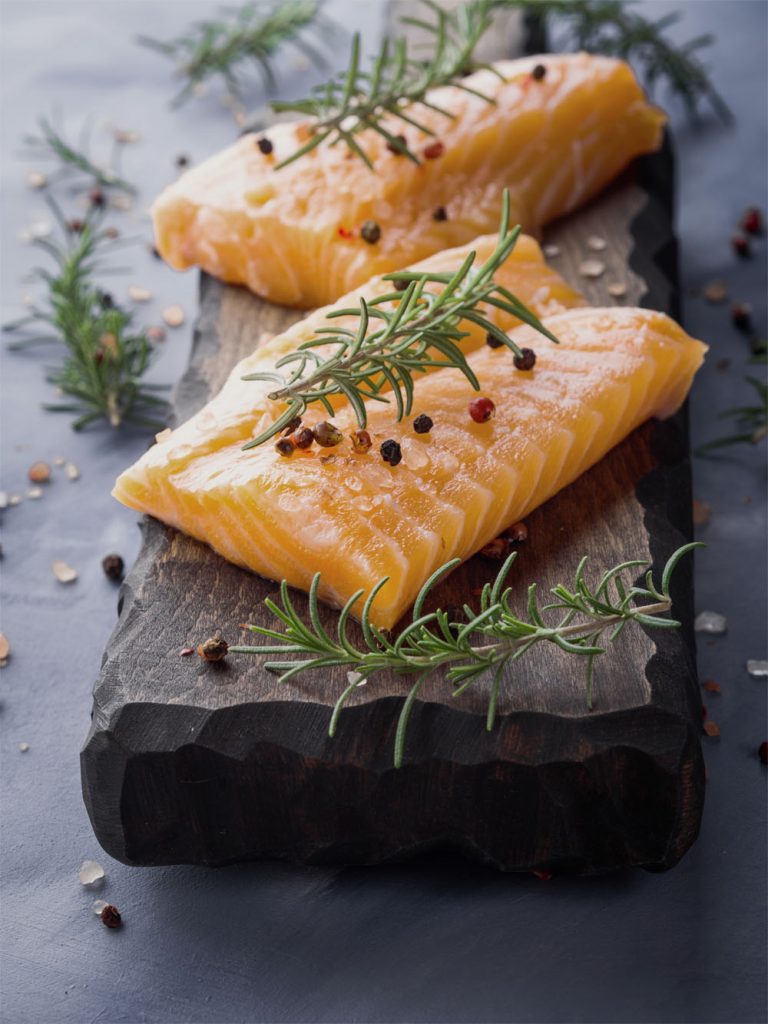 Raw salmon on wooden board with herbs